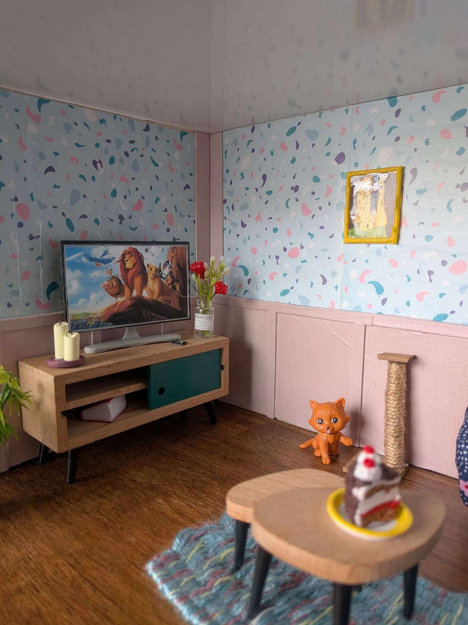 Pormenores da sala em miniatura, com televisão, flores e arranhador